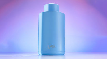 A light blue cylindrical bottle with a matching cap, featuring the 'crank green' logo near the bottom, set against a soft purple and blue gradient background.